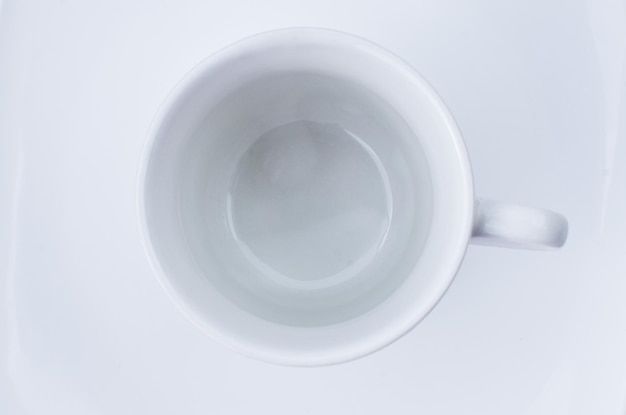 Taza vacía de porcelana refinada destacada sobre un plato blanco que transmite refinamiento y buen gusto.