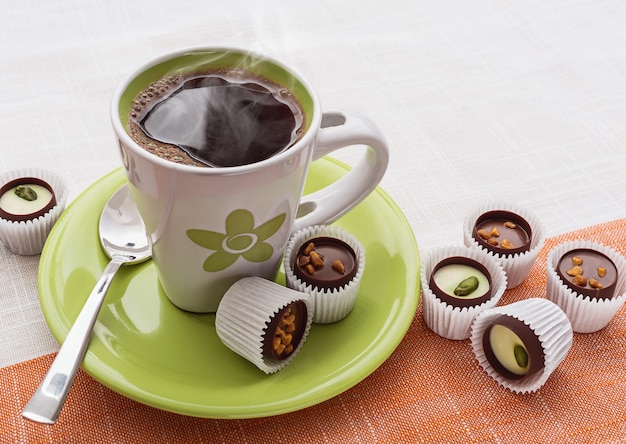 Taza verde de café y chocolates