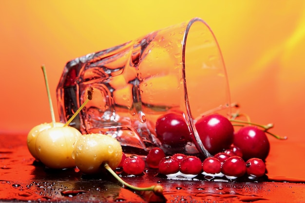 Taza de vidrio transparente con cerezas sobre un fondo tonificado Primer plano de bayas con gotas de agua