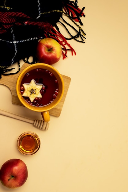 Tazas amarillas de té de bayas calientes con manzanas en la tabla de cortar de madera Bufanda Miel Otoño Concepto de comodidad