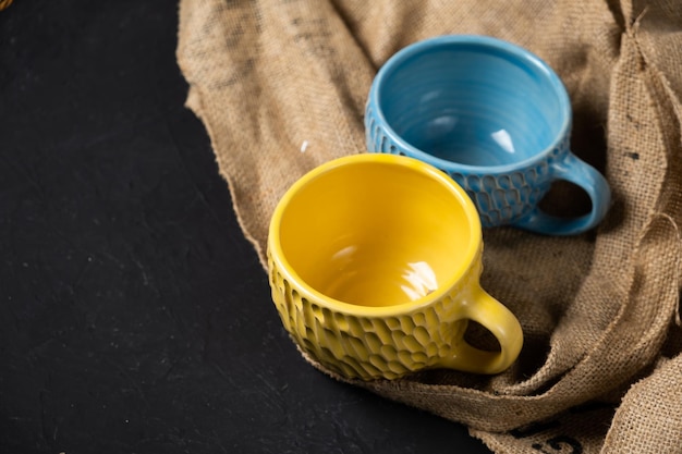 Tazas azules y amarillas aisladas en un fondo negro