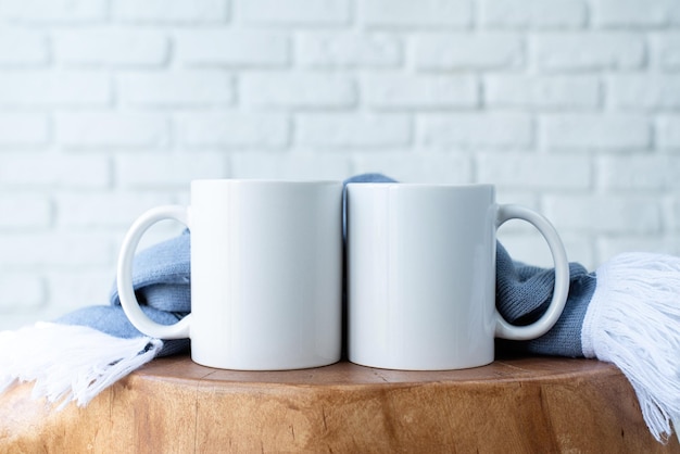 Tazas blancas con bufanda en mesa moderna de madera