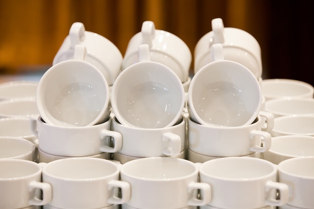 Tazas blancas para el té amontonadas en la mesa para tomar café