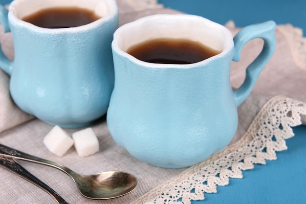 Tazas de café con azúcar y servilleta sobre mesa de madera