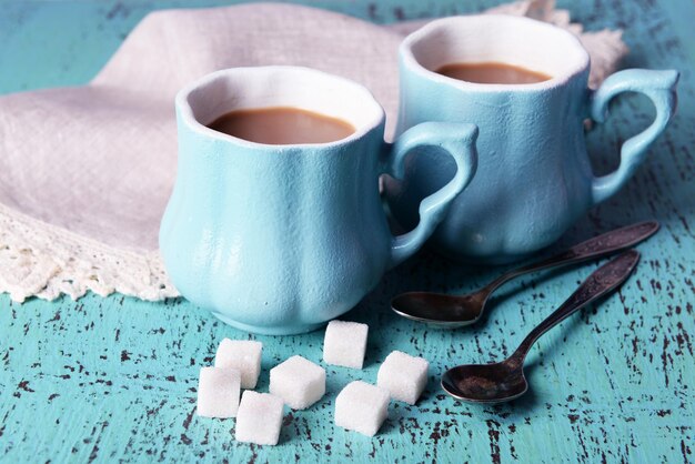 Tazas de café con azúcar y servilleta sobre mesa de madera