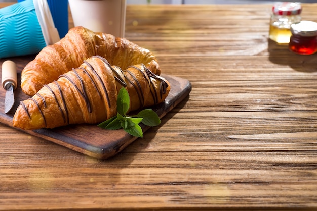 Tazas de café y dos croissants en la calle en Croissant Cafe