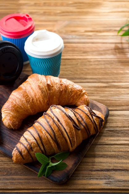 Tazas de café y dos croissants en la calle en Croissant Cafe