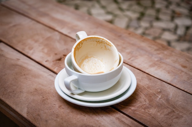 Tazas de café con leche vacías sucias en platillos sobre un fondo de madera