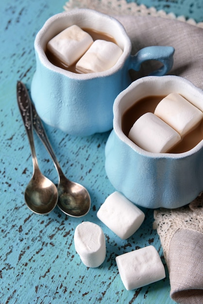 Tazas de café con malvavisco y servilleta en mesa de madera