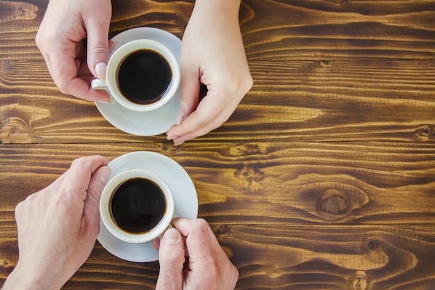 Tazas con un café en manos de hombres y mujeres.