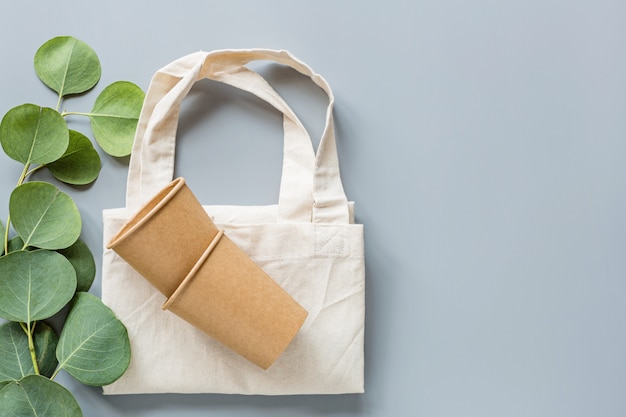 Foto las tazas de café de papel natural ecológico y la bolsa de compras planas yacían sobre fondo gris. concepto de estilo de vida sostenible.