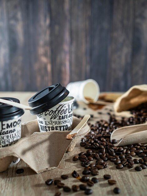 Tazas de café de papel reciclado con granos de café sobre fondo de madera vieja café para llevar