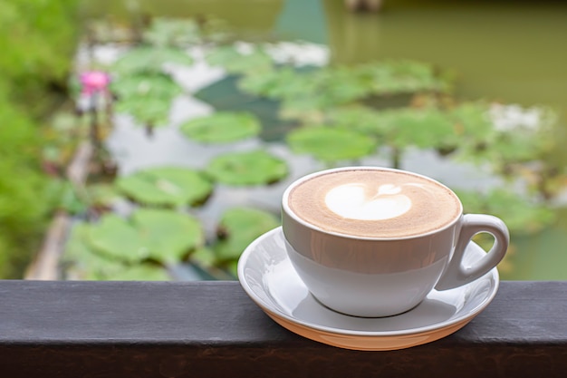 Tazas de café plato blanco con el maquillaje en forma de corazón en balcones de hierro