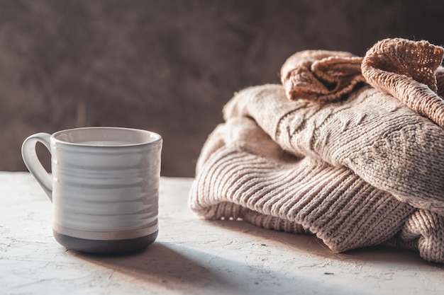 Tazas de café con suéteres tejidos de cálidos colores pastel