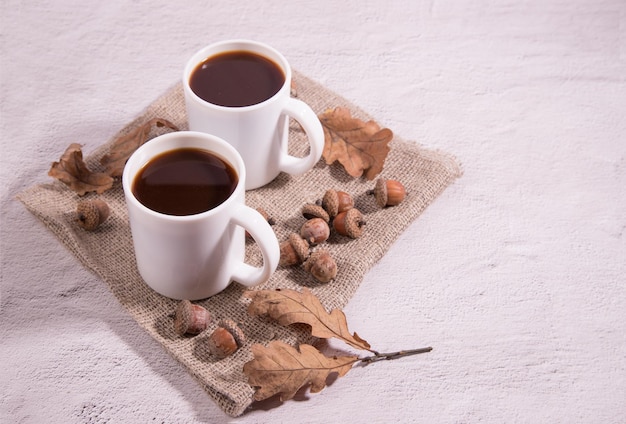 Tazas de café de vidrio hechas de bellotas en una servilleta con bellotas y hojas de roble sobre un fondo claro Altern