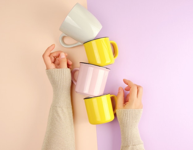 Las tazas de cerámica apiladas están apoyadas por una mano femenina.