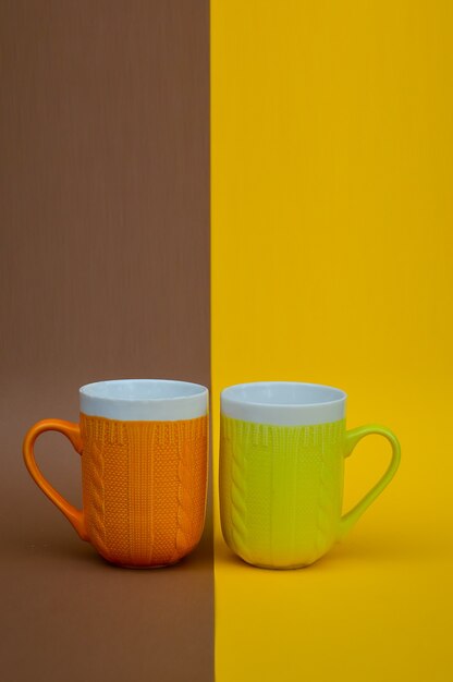 Foto tazas de cerámica con un patrón de punto de color naranja y amarillo sobre un fondo amarillo pardo