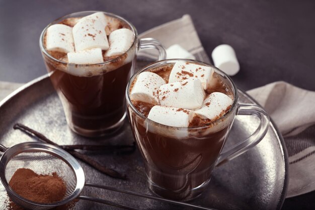 Tazas de chocolate caliente con malvaviscos en primer plano de la bandeja