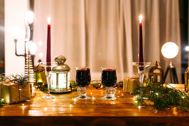 Tazas de glintwine en la mesa decorada con velas