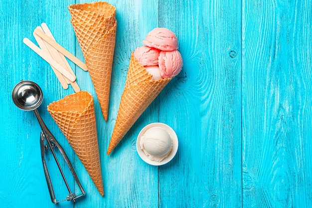 Tazas de gofres de helado de bayas y una cuchara sobre un fondo azul