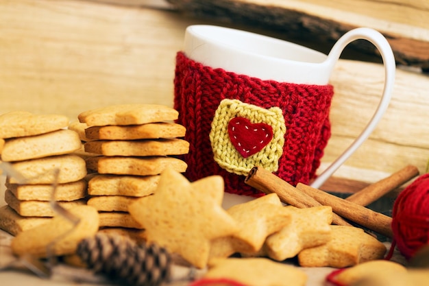 Tazas de lana tejidas en una mesa de madera y hermoso y delicioso pan de jengibre navideño