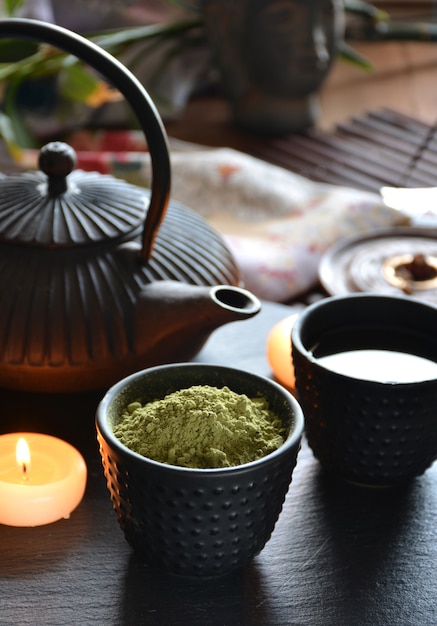 Tazas llenas de tetera japonesa de agua caliente e incienso y velas