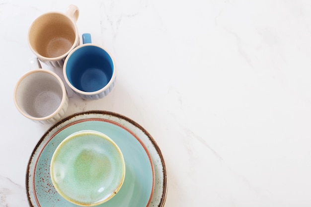 Tazas y platos de cerámica sobre mesa de mármol blanco