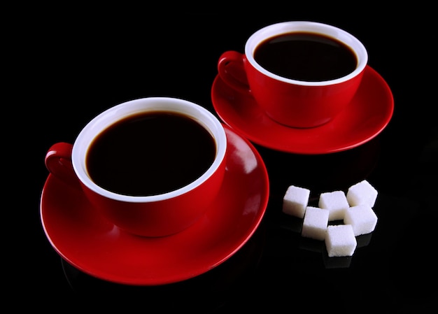 Tazas rojas de café fuerte y azúcar aisladas en negro