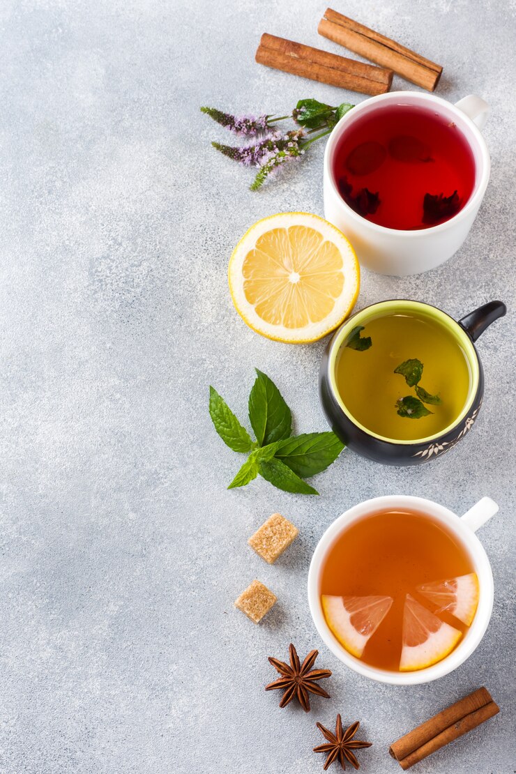 Tazas con té diferente Rojo, verde y negro en mesa gris. Menta y limón, canela con azúcar moreno y anís.