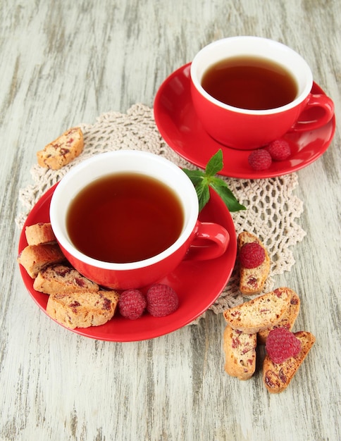 Tazas de té con galletas y frambuesas en primer plano de la mesa