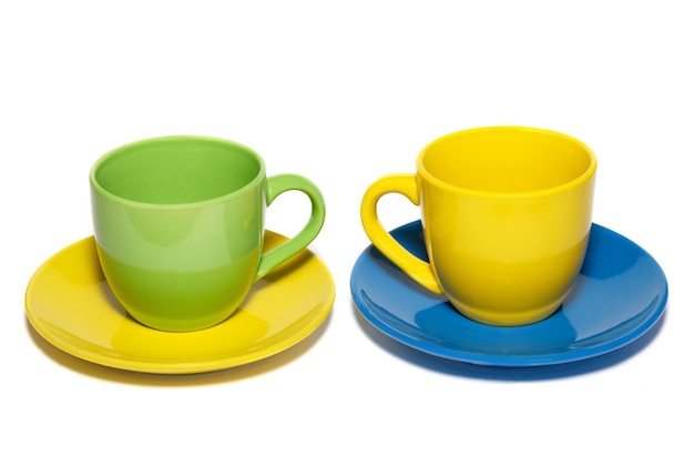 Tazas de té y platillos de colores aislados en blanco.