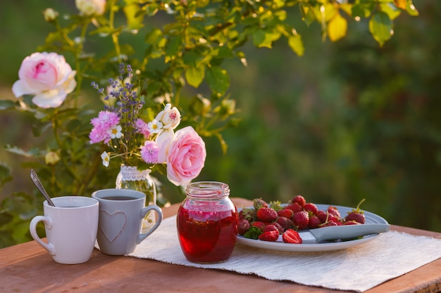 Foto tazas de té con rosas rosadas en una mesa de madera en la mañana