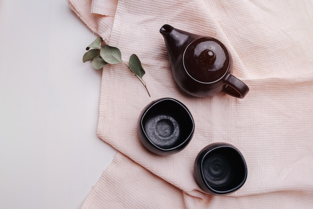 Tazas y tetera barnizadas en negro sobre una toalla de cocina a cuadros