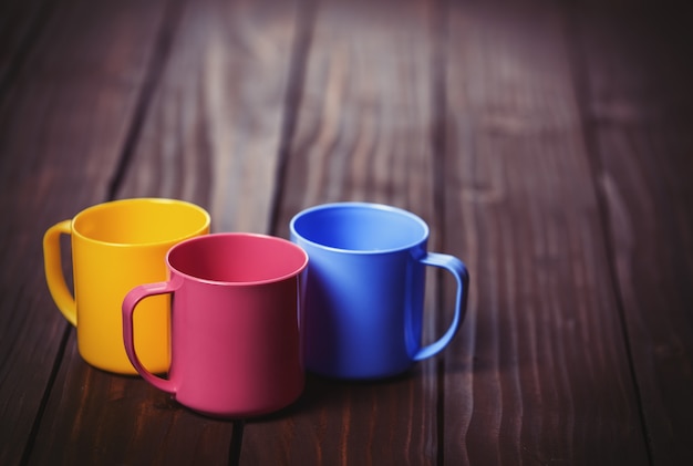 Tazas de tres colores sobre mesa woodent