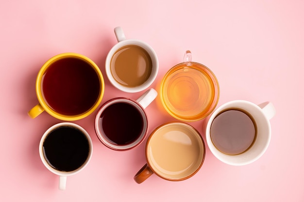 Tazas vasos con varias bebidas tradicionales café té jugo sobre fondo rosa Diseño plano vista superior Concepto de bebidas