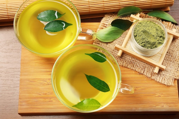 Tazas de vidrio de té verde matcha en primer plano de la tabla de cortar de madera