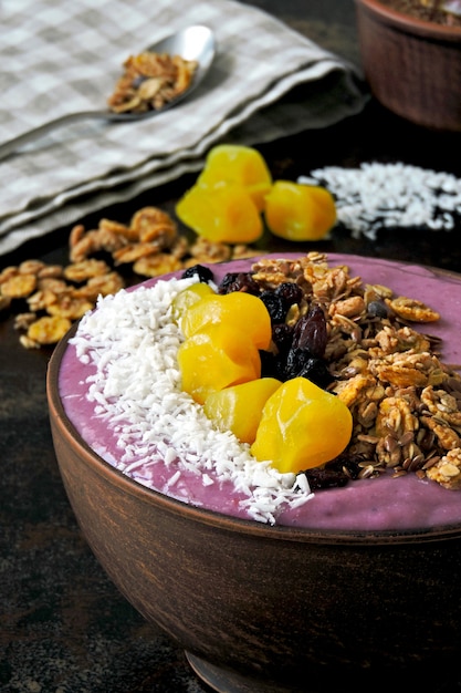 Tazón de acai colorido brillante con granola y frutos secos.