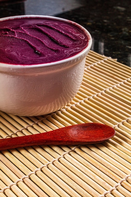 Tazón de Acai en un mantel de bambú con una cuchara al lado.