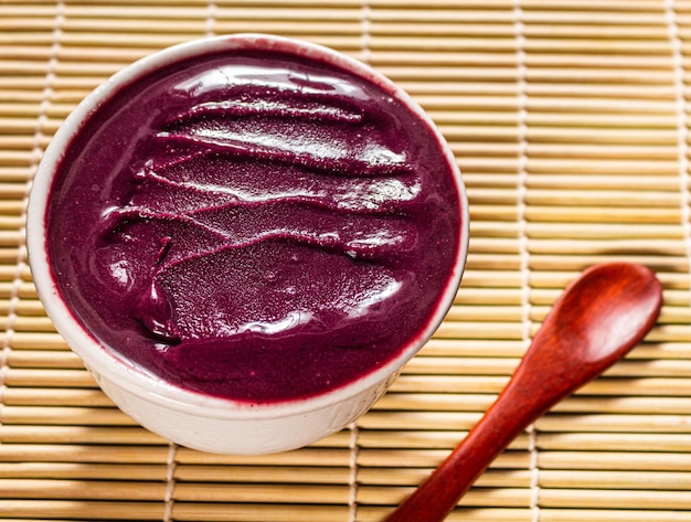 Foto tazón de acai en un mantel de bambú con una cuchara.