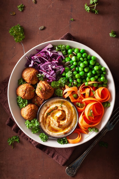 Tazón de almuerzo vegano saludable con falafel hummus zanahoria cintas repollo y guisantes