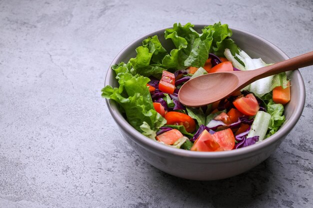 Tazón de almuerzo vegano saludable hecho de varias verduras frescas crudas sobre fondo gris