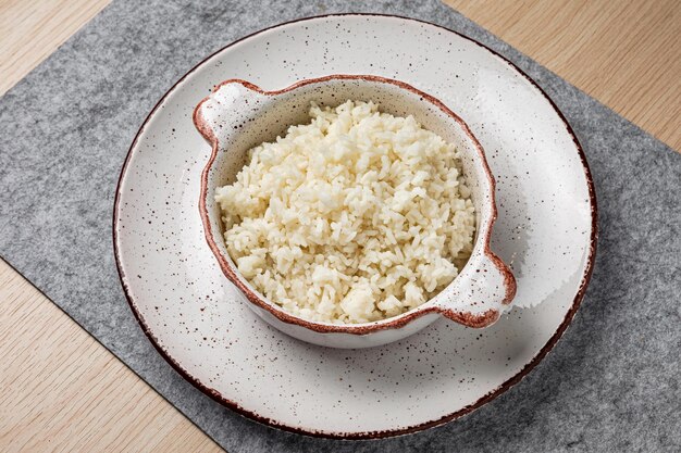 Un tazón de arroz hervido en un plato, primer plano