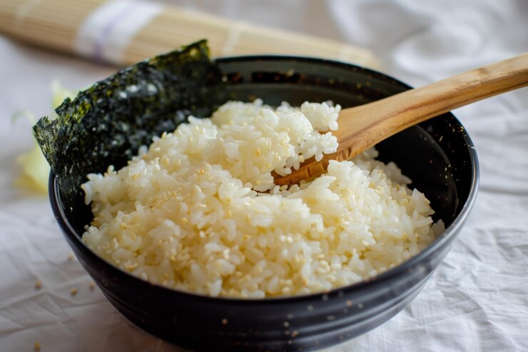 Un tazón de arroz sushi con una paleta de madera
