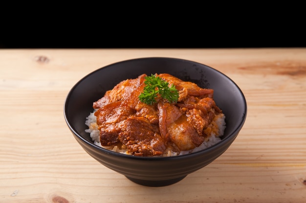 Tazón de arroz de vientre de cerdo picante japonés sobre mesa de madera