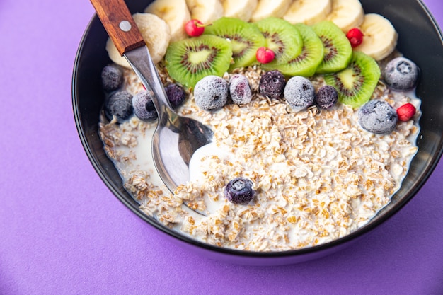 tazón de avena fruta plátano kiwi bayas arándanos listo para comer comida bocadillo en la mesa