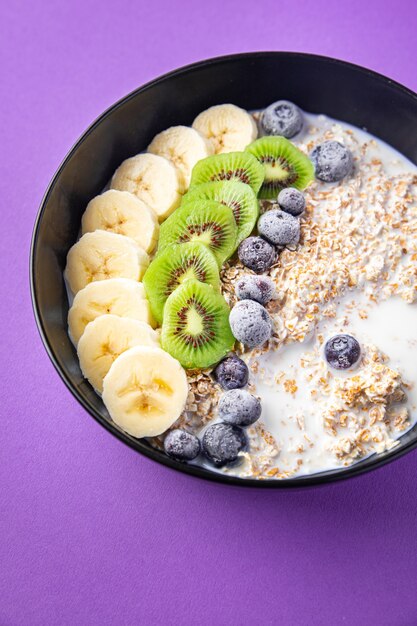 tazón de avena fruta plátano kiwi bayas arándanos listo para comer comida bocadillo en la mesa