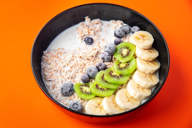 tazón de avena fruta plátano kiwi bayas arándanos listo para comer comida bocadillo en la mesa