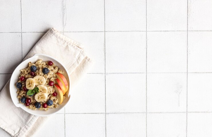 Tazón de avena con fruta sobre un fondo de baldosas blancas.