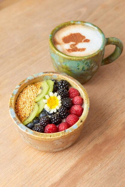 Tazón de avena con mora, frambuesa, amaranto y kiwi en una mesa de madera