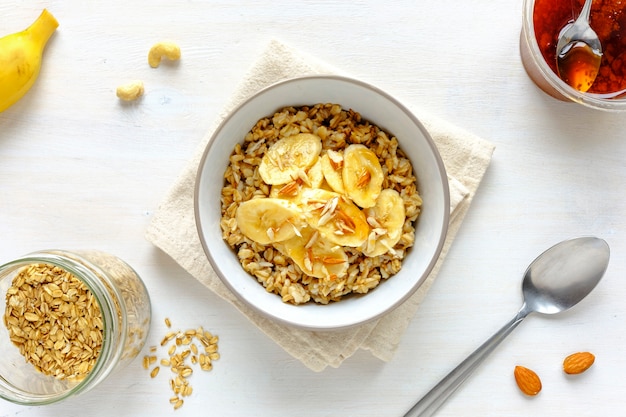 Tazón de avena con plátano contra la mesa blanca